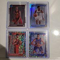 Photo of four basketball rookie cards in protective sleeves on white surface
