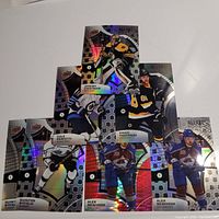 Seven Upper Deck Allure rookie hockey cards arranged on flat surface featuring players Quinton Byfield, Cole Perfetti, David Pasternak, Jeremy Swayman, and Alex Newhook with holographic foil accents.