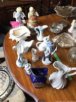 Wide view of various ceramic figurines and decorative pitchers on a wooden table