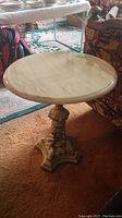 Full view of round marble top table set on carpet, showing overall condition and items around.