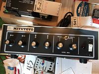 Front view of Mitutoyo camera control unit showing six adjustment knobs including level and directional controls, power switch, and indicator light.