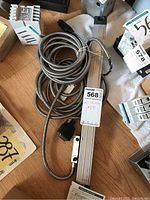 Linear scale laid flat on floor with coiled cables attached, showing Mitutoyo tag and connector ends.