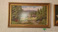 Full view of the framed needlepoint art showing the entire landscape scene and gold frame.