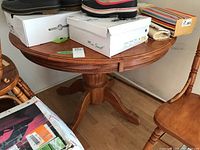 Round oak table seen from the side with some items on top. Shows table surface and pedestal base.