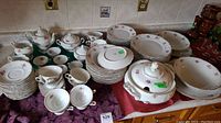 Full view of all pieces in set showing plates in stacks, cups, saucers, teapot, creamer, sugar bowl, and tureen on table surface.