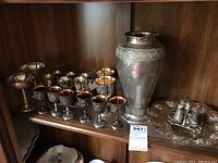 Shelf display of holloware set including vase, chalices, tray, and salt and pepper shakers set