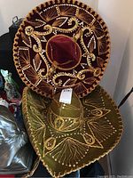 Two sombreros stacked with intricate gold embroidery and sequins on a table.
