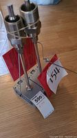 Photo of two Onicon Thermowalls 6325-2 temperature sensors with metal probes fixed in a stand with attached red instruction tags and a paper lot number tag on a wooden floor.