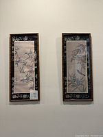 Pair of two framed Asian-style prints with birds and floral motifs hung on wall.