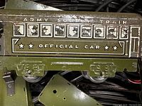 Close-up of green Army Super Train official car with soldier illustrations and star markings, showing details of metal wheels and tin construction.