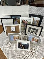 Overall view of collection of picture frames in black and white colors on lace tablecloth