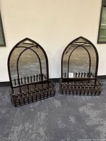 Pair of mirrored gothic iron wall planters side by side on carpet floor