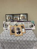 Photo showing a set of black textured frames and natural wood frames arranged on a patterned surface against a beige wall.