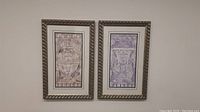 Photo showing both framed paintings side by side on a wall, featuring ornate vases in classic style with silver textured frames.