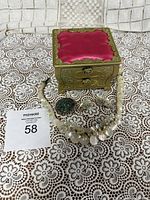 Photo of the jewelry box showing the front and side, along with all jewelry pieces laid out on a lace tablecloth.