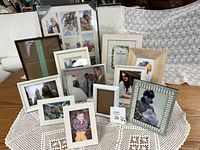 Full set of 11 picture frames displayed on a lace tablecloth, showing variety of sizes and styles with photos inside.