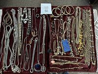 Full view of all jewelry pieces laid out on maroon velvet surface showing the variety of chains, bracelets, rings, and earrings.
