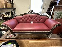 Front view of entire settee showing tufting, arms, nailhead trim and legs.