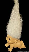 Side view of the 2-inch crawling troll mini baby doll showing the nude plastic body and long white hair.