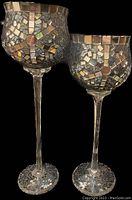 Pair of two stemmed mosaic glass candle holders with detailed mosaic and mirrored patterns on the cup portion and stems with mosaic bases.