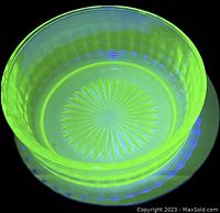 Photo of the 4-inch Jefferson vaseline glass berry bowl glowing bright neon yellow-green under ultraviolet black light showing its vaseline glass property.