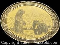 Front view of oval silver-colored belt buckle featuring etched design of two bears with a twisted rope border.