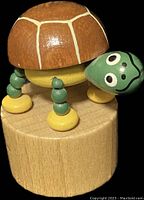 Front view of the colorful wooden dancing turtle toy showing head, shell, legs, and base