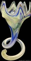 Side angle showing the swirling blues, greens, and white colors on hand blown glass vase with a coiled base and pointed rim edges