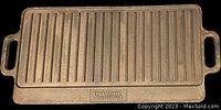 Full view of the rectangular cast iron griddle with ridged grilling surface and flat, loop handles on both ends.
