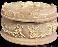 Front angled view of the pink carved stone oval jewelry box showing detailed floral relief and domed lid.