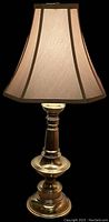 Full view of brass lamp with one fabric shade attached, turned column brass base with glossy finish, light beige shade with dark trim