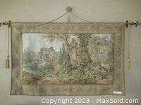 Full view of the tapestry wall hanging showing overall condition and hanging method with decorative cord and metal rod.