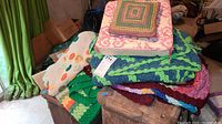 Pile of colorful handmade crocheted afghans, topped with two throw pillows
