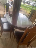 Side view of oval-shaped wooden dining table with six chairs around, showing table surface and chair designs