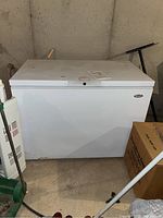 Wood's chest freezer, white color, rectangular shape, front and side view in a basement setting.