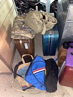 Multiple vintage and soft-sided luggage including tote bags and hard suitcases arranged on the floor showing condition and style