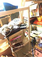 Front view of the white plastic shelf with contents including a turntable, headphones, and portable radios.