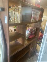 Front and side view of vintage double bookcase showing open shelving and storage compartments with doors below, placed in garage environment.