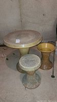 Photo showing the vintage plastic outdoor table with two matching stools, one stool missing the top.
