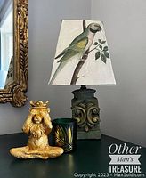 Front view of the small green table lamp with parrot motif lampshade and textured base.