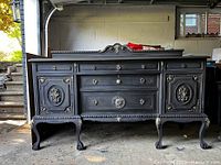 Full front view of the black painted carved wood sideboard showing entire piece and decorative moldings.