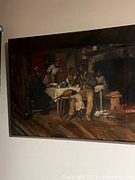 Photo shows the original canvas wall art featuring a detailed image of several people in a warm interior setting with table and fireplace.