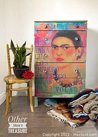 Full front view of colorful dresser with painted Frida Kahlo portrait and decorative text, also showing crystal knob handles.