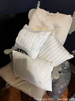 Three small white cushions with different textures on a wooden rocking chair against a dark background.
