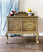 Front view of vintage buffet showing carved wood details, two drawers, two doors, decorative floral painted design, cabriole legs.