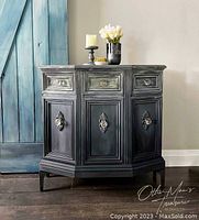 Front view of vintage cabinet showcasing ombre paint finish with soft green and grey hues, three drawers, three cupboard doors with decorative handles, and new legs added for height.