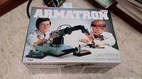 Box top of Radio Shack Armatron 7A3 showing children playing with the robotic arm toy.
