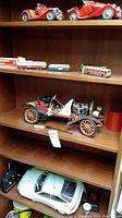 Large vintage-style red cars and small bus models on shelf