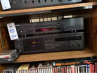 Two black stereo components on wooden shelf: Yamaha CD-S300 on top and Yamaha KX-530 cassette deck below