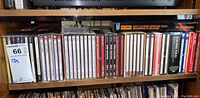 Shelf with over 30 CDs in jewel and box cases visible. Titles include classical and blues music.